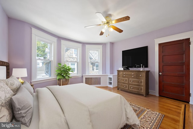 bedroom featuring ceiling fan, light wood-type flooring, and radiator heating unit