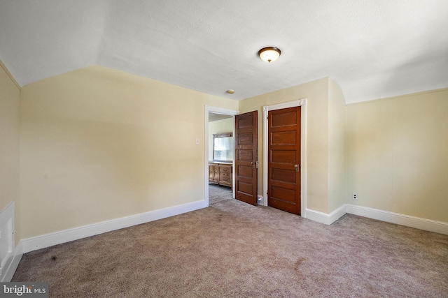 unfurnished bedroom featuring carpet and lofted ceiling