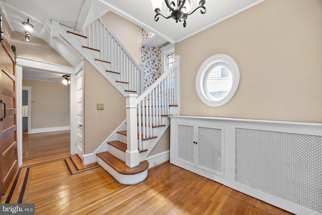 stairway with hardwood / wood-style floors, ceiling fan with notable chandelier, and a barn door