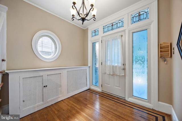 entryway featuring hardwood / wood-style floors, ornamental molding, and an inviting chandelier