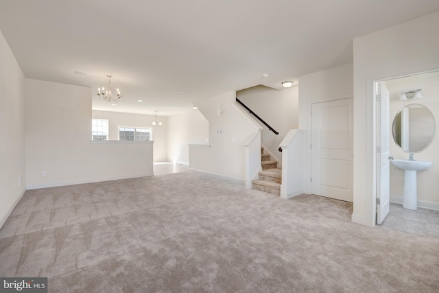 unfurnished living room with light colored carpet, an inviting chandelier, and sink