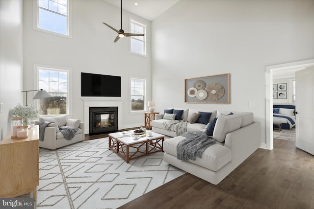 living room featuring ceiling fan, a towering ceiling, and hardwood / wood-style flooring