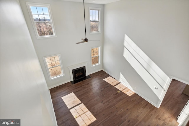 unfurnished living room featuring a high ceiling, dark hardwood / wood-style floors, and ceiling fan