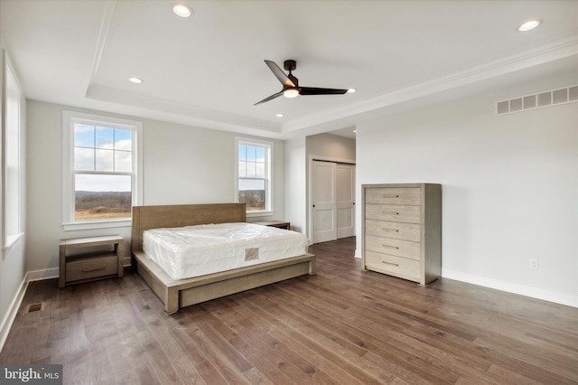 unfurnished bedroom with hardwood / wood-style flooring, ceiling fan, a closet, and a tray ceiling