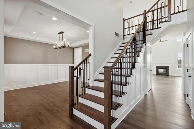 stairs with ceiling fan with notable chandelier and wood-type flooring