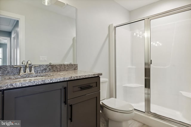 bathroom featuring vanity, toilet, and a shower with door