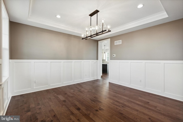 unfurnished dining area featuring a notable chandelier, dark hardwood / wood-style flooring, ornamental molding, and a tray ceiling