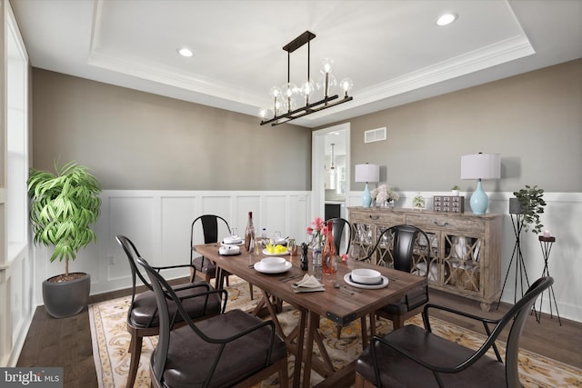 dining room featuring a chandelier, hardwood / wood-style floors, a raised ceiling, and ornamental molding