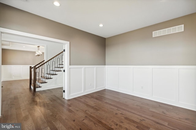 unfurnished room with dark wood-type flooring and a chandelier