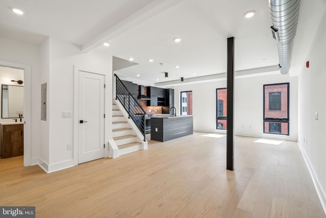 basement with electric panel, light hardwood / wood-style flooring, and sink