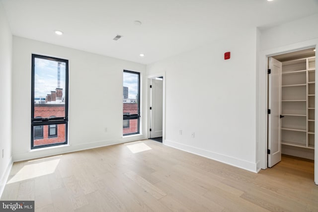 unfurnished bedroom featuring light wood-type flooring, a walk in closet, and a closet