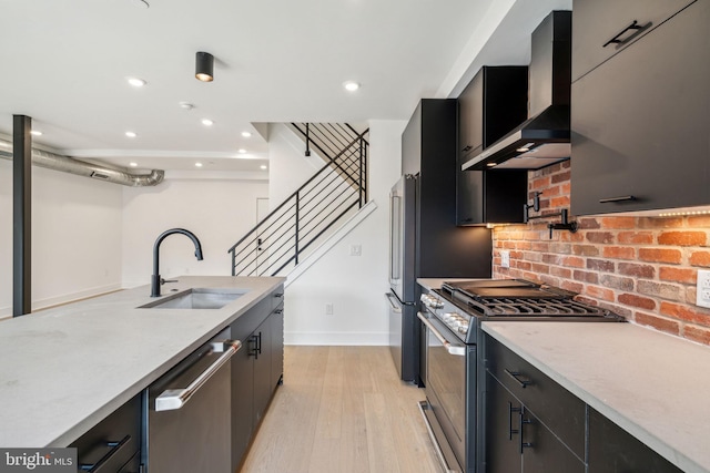 kitchen with sink, light hardwood / wood-style flooring, high end appliances, and wall chimney range hood