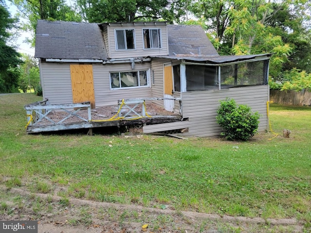 rear view of house featuring a sunroom and a lawn