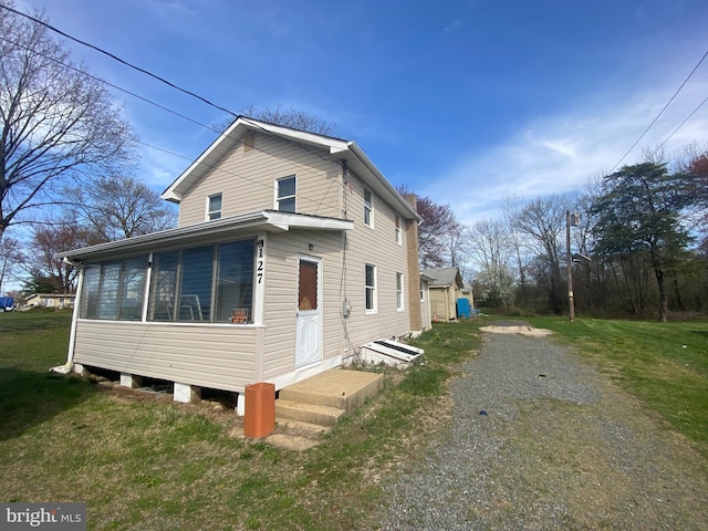 view of side of property with a lawn and a sunroom