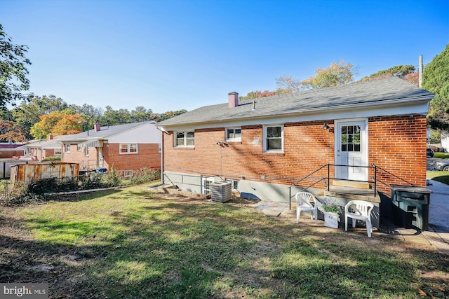 back of property with central air condition unit and a yard