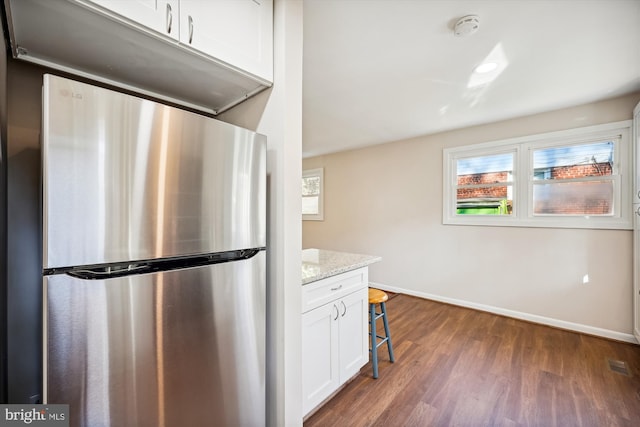 kitchen featuring dark hardwood / wood-style floors, light stone countertops, stainless steel fridge, and white cabinetry