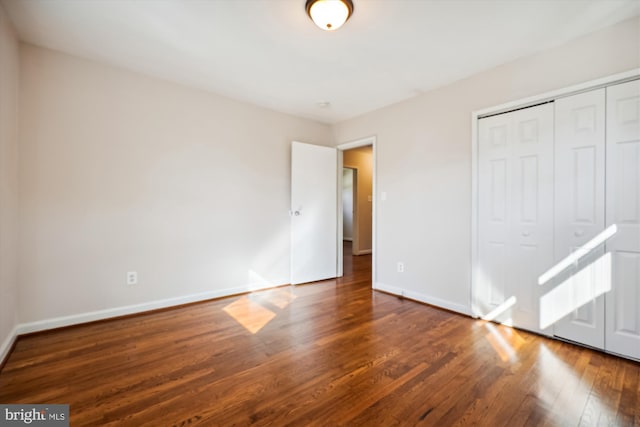 unfurnished bedroom with a closet and dark hardwood / wood-style flooring