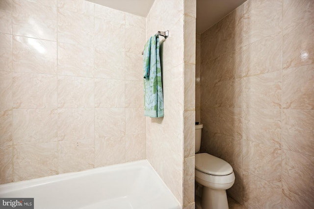 bathroom featuring tile walls, a bathtub, and toilet