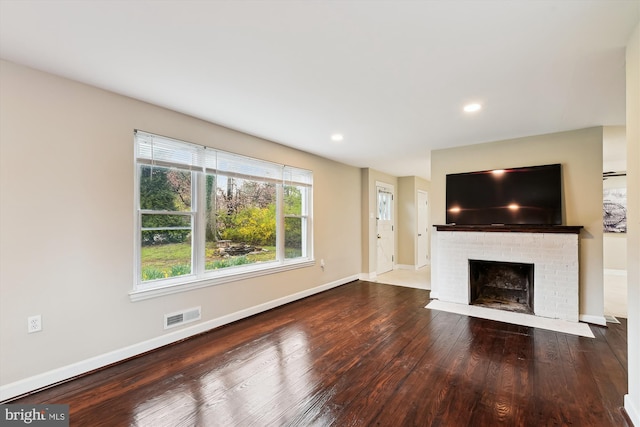 unfurnished living room with visible vents, baseboards, a brick fireplace, recessed lighting, and hardwood / wood-style floors