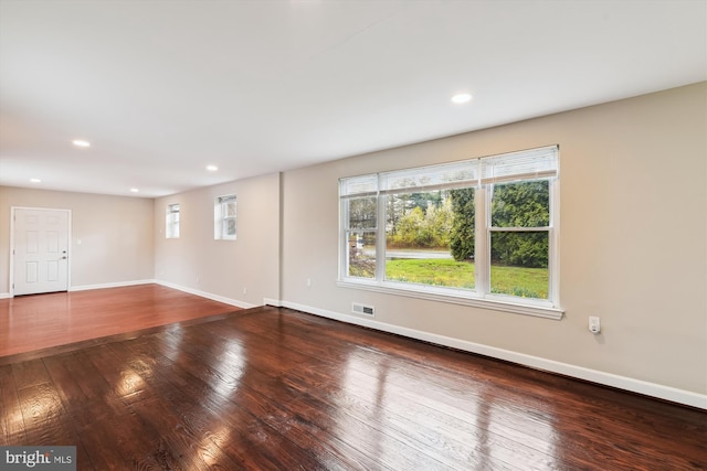 unfurnished living room featuring visible vents, baseboards, and hardwood / wood-style floors