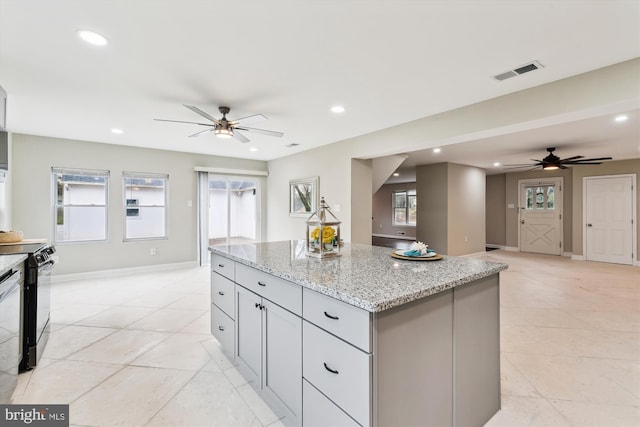 kitchen featuring visible vents, black electric range, a ceiling fan, and a kitchen island