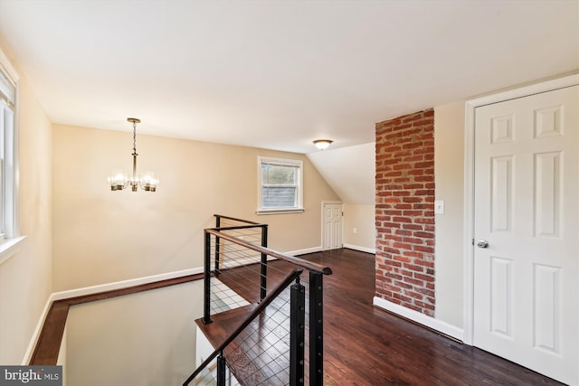 additional living space featuring dark wood-type flooring, an inviting chandelier, and baseboards