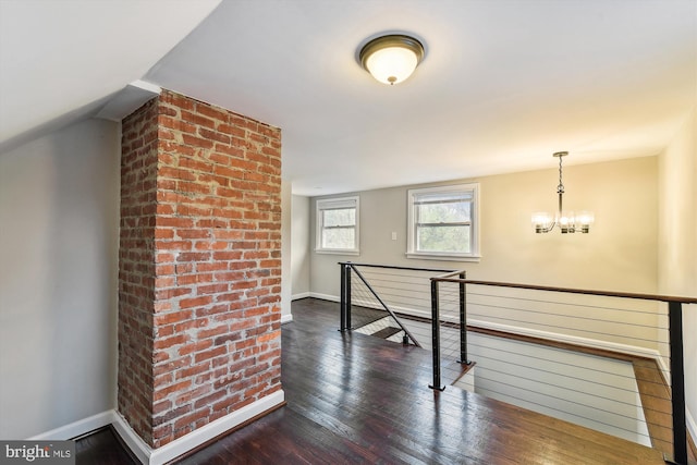 interior space with dark wood-style flooring, baseboards, an upstairs landing, and a notable chandelier