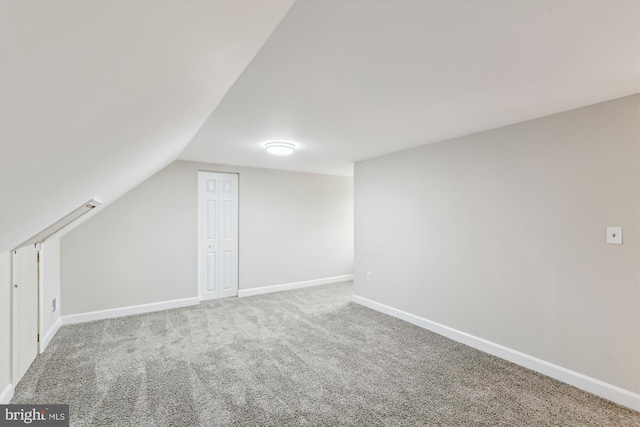 additional living space with baseboards, lofted ceiling, and carpet