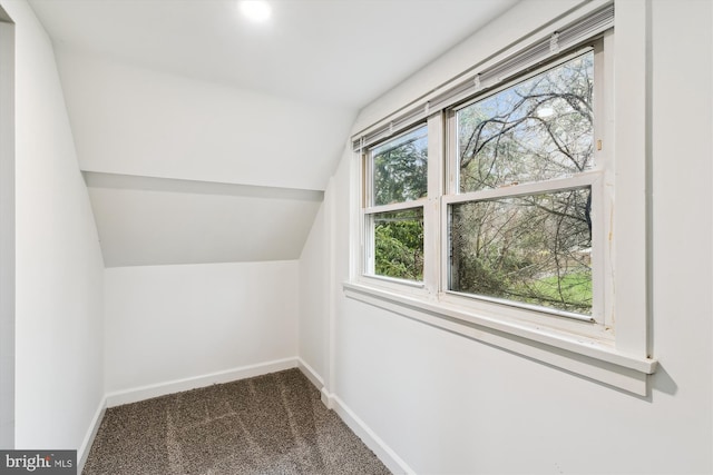 bonus room with dark carpet, baseboards, and vaulted ceiling