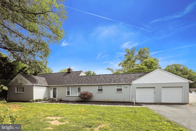 ranch-style home with aphalt driveway, a front lawn, a chimney, and an attached garage