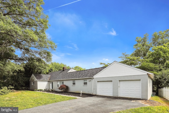 view of front facade featuring roof with shingles, driveway, a front lawn, a garage, and fence