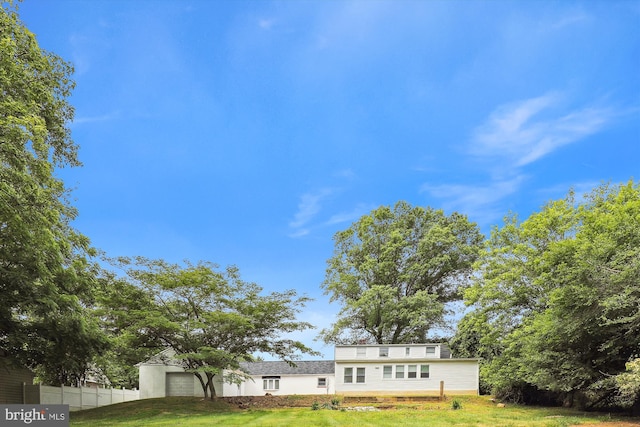 view of front of house featuring a garage, fence, and a front lawn