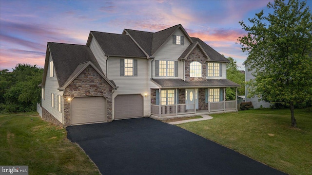 view of front of property featuring covered porch, a yard, and a garage