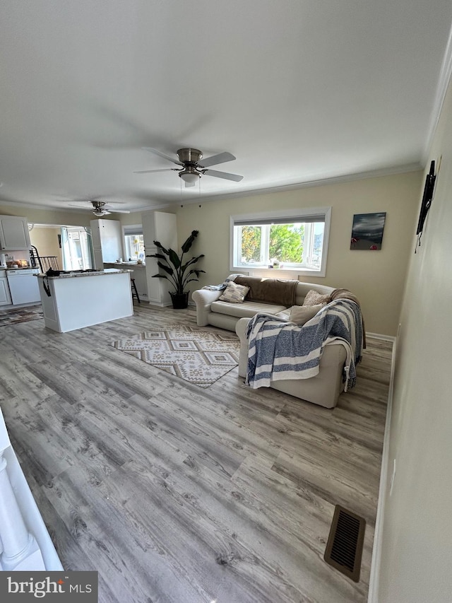 living room with light hardwood / wood-style flooring, ornamental molding, and ceiling fan