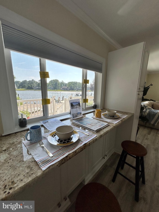 dining space with crown molding, a water view, and hardwood / wood-style floors