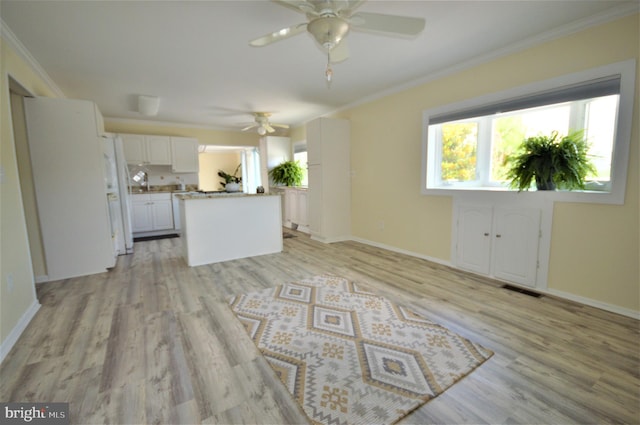 unfurnished living room with crown molding, ceiling fan, and light wood-type flooring