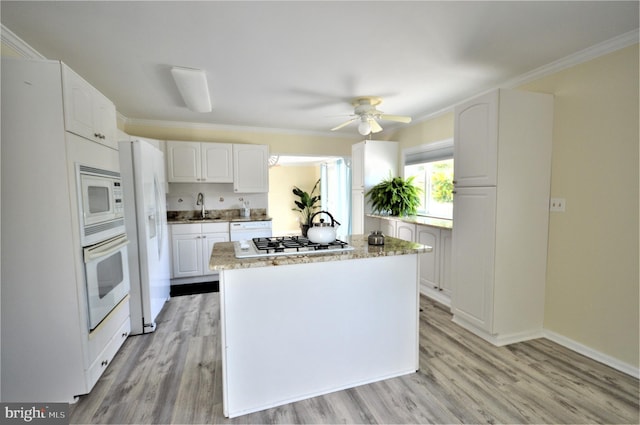 kitchen featuring white appliances, ornamental molding, light wood-type flooring, and white cabinets