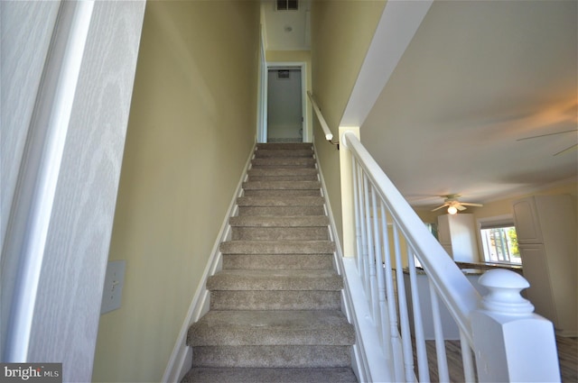 stairway featuring ceiling fan