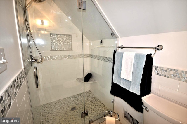 bathroom featuring tile walls, a shower with door, lofted ceiling, and toilet