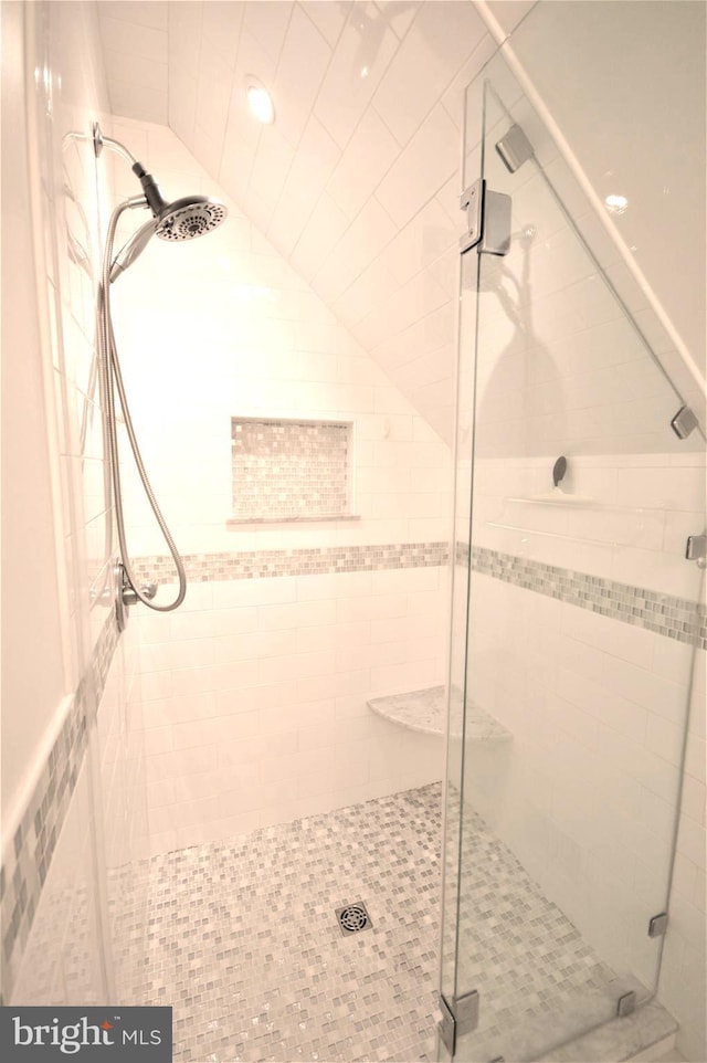 bathroom featuring lofted ceiling and a shower with door