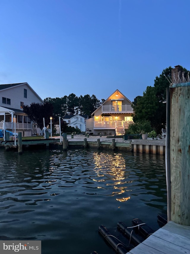 view of dock with a balcony and a water view