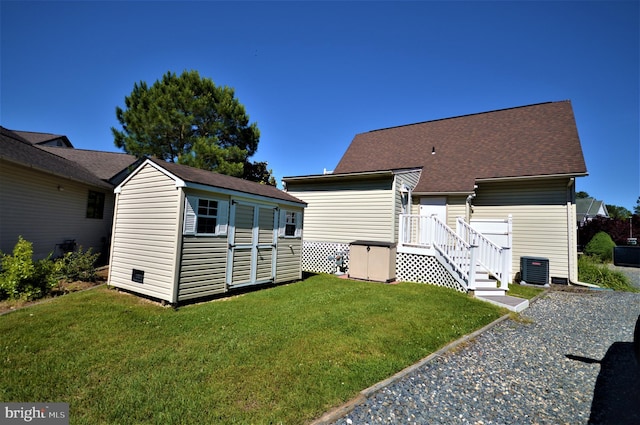 rear view of house featuring cooling unit, a storage shed, and a yard