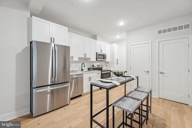 kitchen with white cabinetry, sink, stainless steel appliances, and light hardwood / wood-style floors