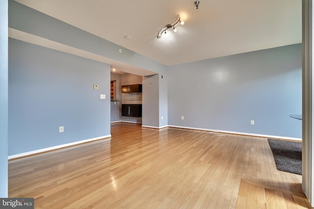 unfurnished living room featuring rail lighting and light hardwood / wood-style floors