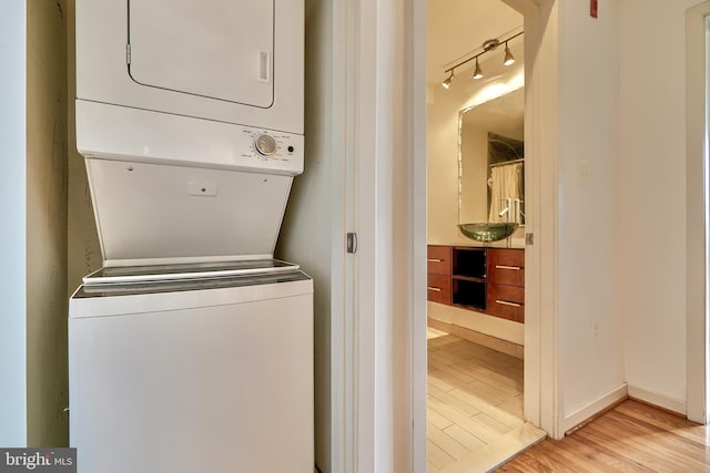 washroom featuring stacked washer / dryer and light wood-type flooring