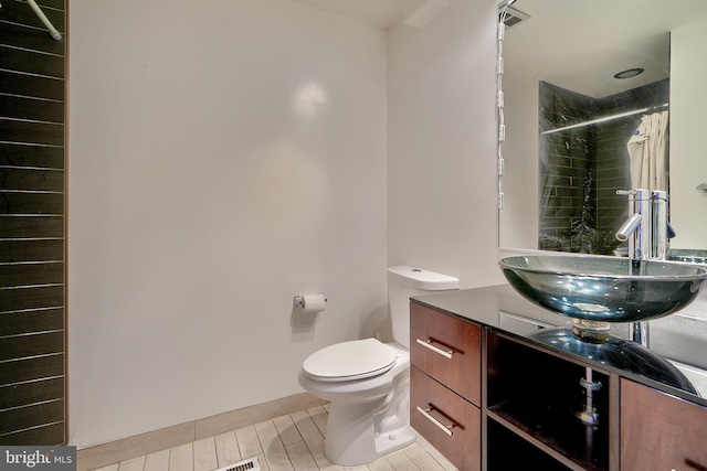 bathroom featuring toilet, vanity, and curtained shower