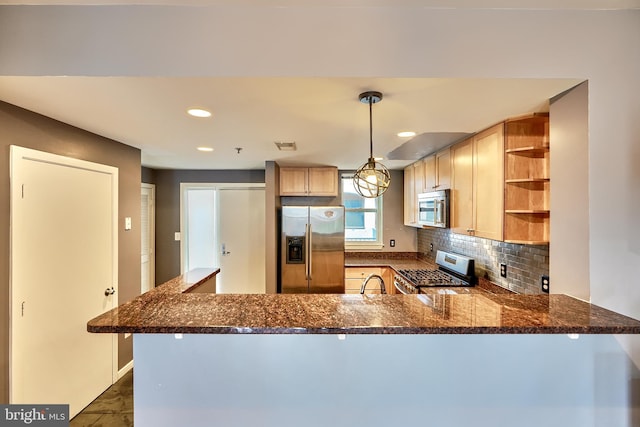 kitchen featuring kitchen peninsula, stainless steel appliances, decorative backsplash, dark stone countertops, and pendant lighting