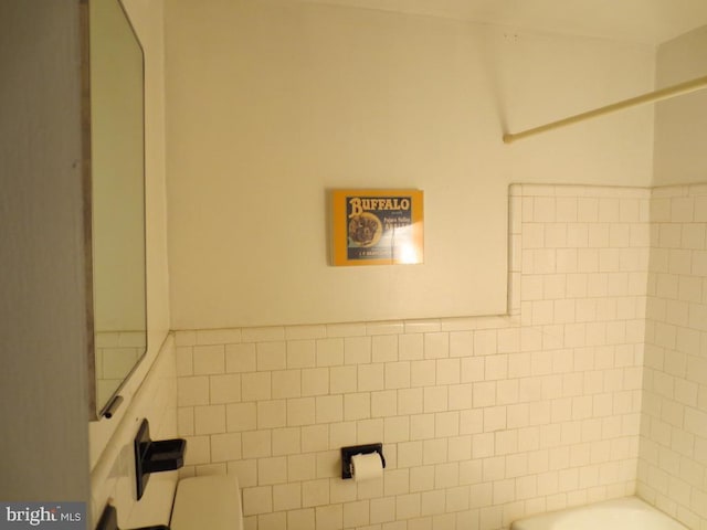 bathroom featuring  shower combination and tile walls