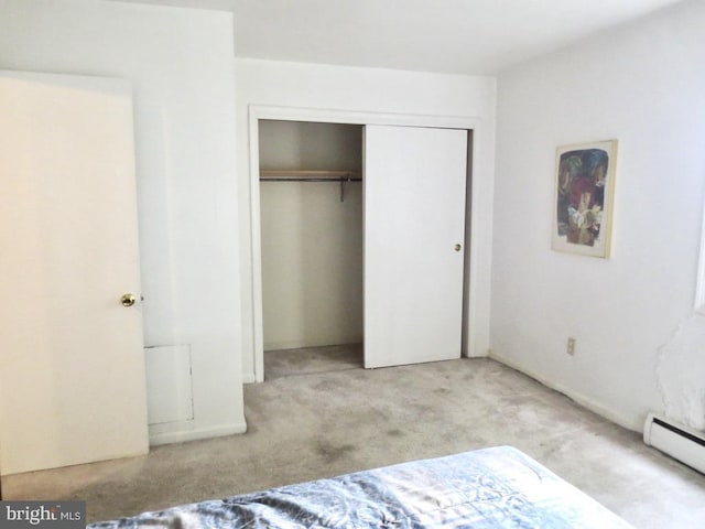 bedroom with a closet, light carpet, and a baseboard radiator