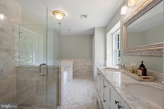 bathroom with tile patterned flooring, vanity, an enclosed shower, and tile walls